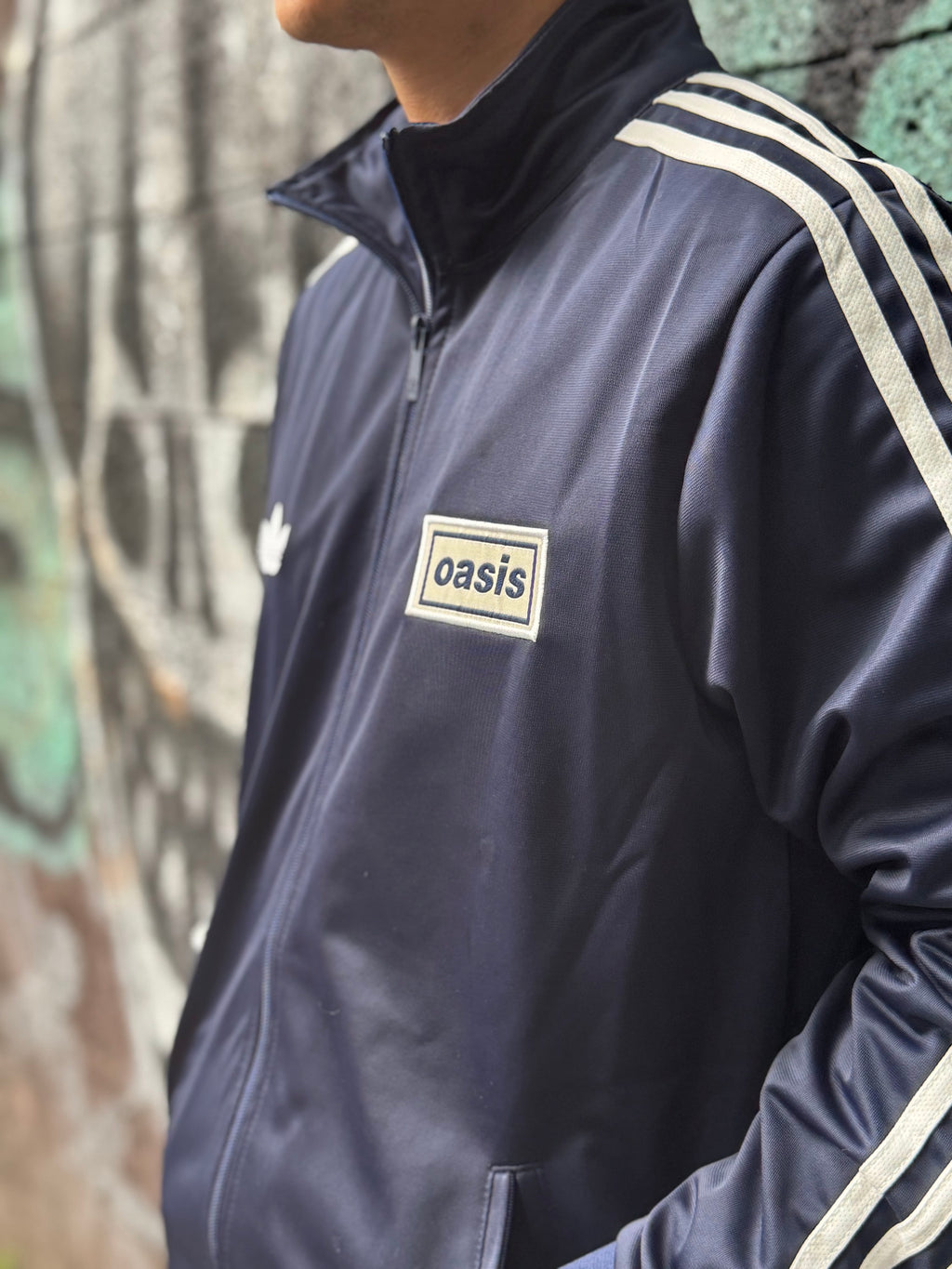 Modelo con la Chamarra Oasis x Adidas Live '25 Azul Marino