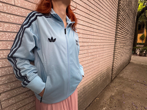 Modelo con la Chamarra Oasis x Adidas Live '25 Celeste
