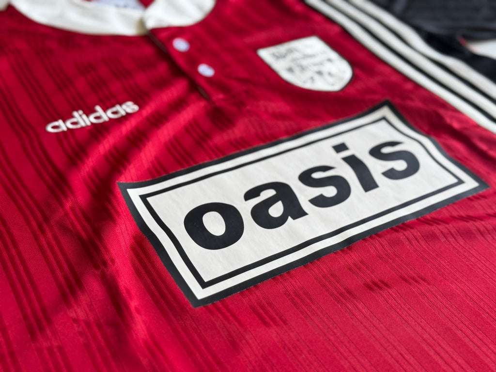 Logo Oasis de la Playera Oasis x Adidas Live '25 Granate